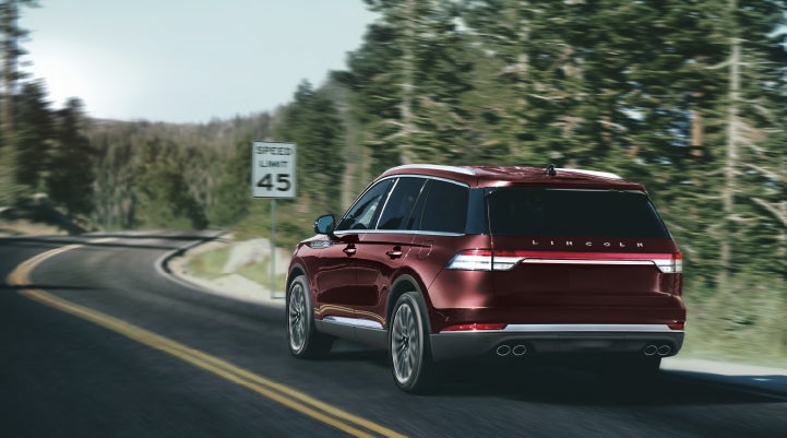 A 2024 Lincoln Aviator® SUV is being driven on a winding mountain road | Baldwin Lincoln in Covington LA