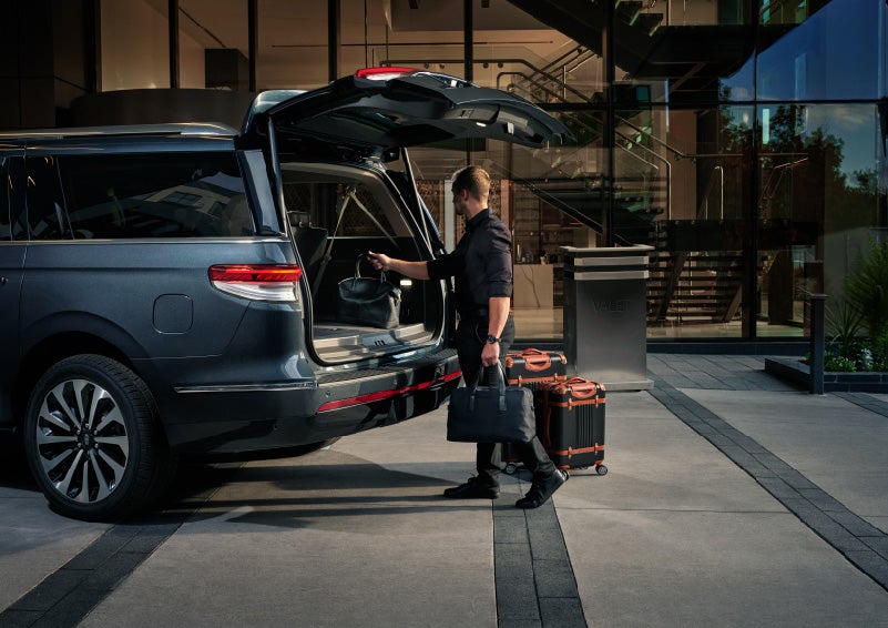 A valet is unloading luggage from the rear cargo area of a 2022 Lincoln Navigator SUV | Baldwin Lincoln in Covington LA