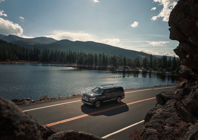 A 2022 Lincoln Navigator SUV is driving along a lake high up in the mountains | Baldwin Lincoln in Covington LA