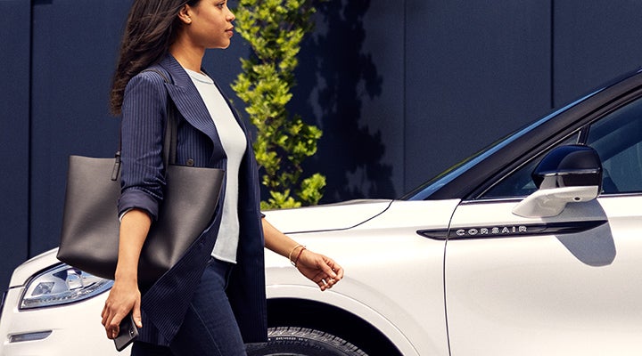 A woman approaches a 2024 Lincoln Corsair® SUV while holding a smartphone. | Baldwin Lincoln in Covington LA